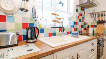 A kitchen with a wooden countertop, a kettle, a toaster, and a colorful backsplash.