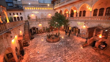 A courtyard with a fountain, potted plants, and a sign reading 'Yildiz Sarayi Konukeleri'.