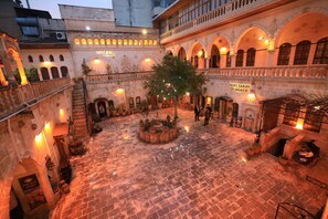 A courtyard with a fountain, potted plants, and a sign reading 'Yildiz Sarayi Konukeleri'.