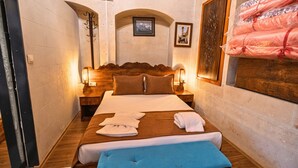Ein Hotelzimmer mit einem hölzernen Bett, zwei Nachttischen mit Lampen, einem großen Spiegel und Blick auf die Stadt.
