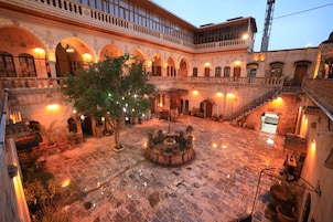 Un patio con una fuente central, suelo de piedra y balcones en arco.