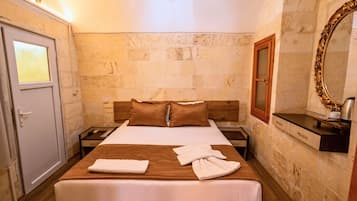 A hotel room with a bed, a nightstand, a wooden headboard, a mirror, and a door.