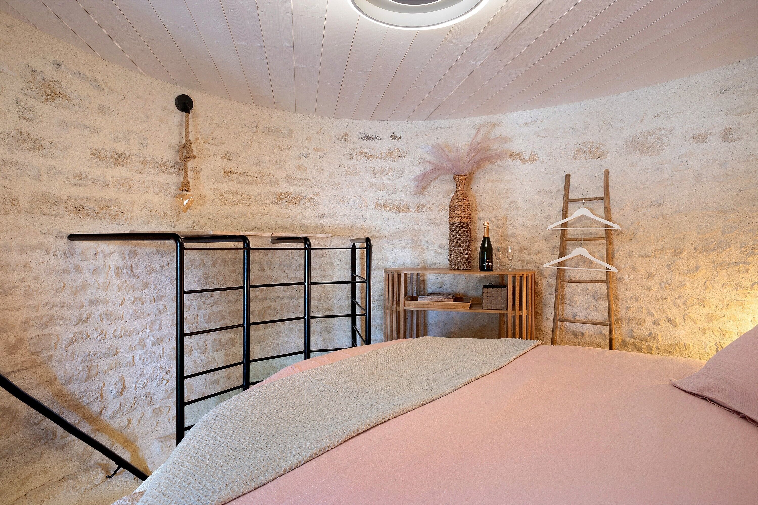Un dormitorio con cama, un estante de madera, una silla colgante y un gancho en la pared.