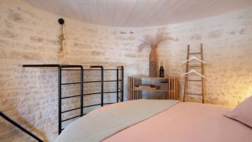Un dormitorio con cama, un estante de madera, una silla colgante y un gancho en la pared.