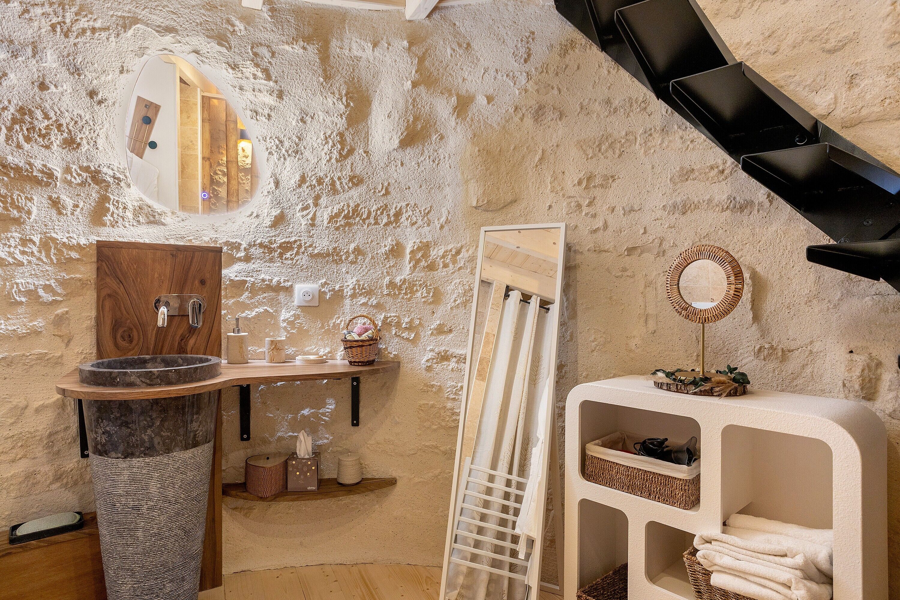 A bathroom with a stone sink, wooden vanity, and a large mirror.