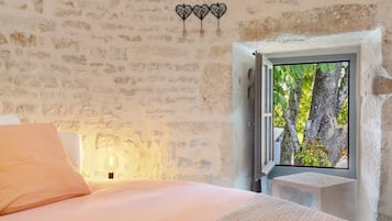 A bedroom with a bed, a window with a view of trees, and a wall with a textured pattern.