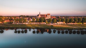 En stad vid en flod med historiska byggnader, en framstående kyrka och ett stilla vattendrag som speglar arkitekturen.