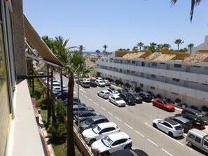 A parking lot with multiple cars and a building with a tiled roof. - 1 Bedroom Apartment at 50 Meters From the Beach (Roquetas de Mar)