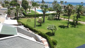 A resort with a swimming pool, palm trees, and a view of the sea. - 1 Bedroom Apartment at 50 Meters From the Beach (Roquetas de Mar)