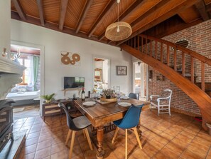 A dining area with a wooden table, chairs, and a television on a stand. - Charming house with AC, pets OK - 4 guests (Parentis-en-Born)