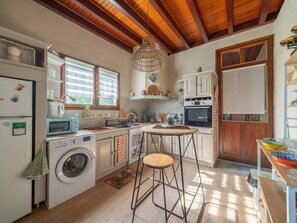 A compact kitchen with a washing machine, microwave, and a small dining area with a stool. - Charming house with AC, pets OK - 4 guests (Parentis-en-Born)