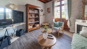 A living room with a television, bookshelf, armchair, and fireplace. - Charming house with AC, pets OK - 4 guests (Parentis-en-Born)