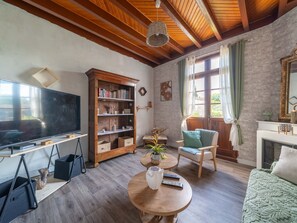 A living room with a television, bookshelf, armchair, and fireplace. - Charming house with AC, pets OK - 4 guests (Parentis-en-Born)