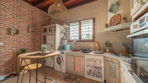 A kitchen with a brick wall, wooden beams, a hanging light fixture, a washing machine, a microwave, and a stove. - Charming house with AC, pets OK - 4 guests (Parentis-en-Born)