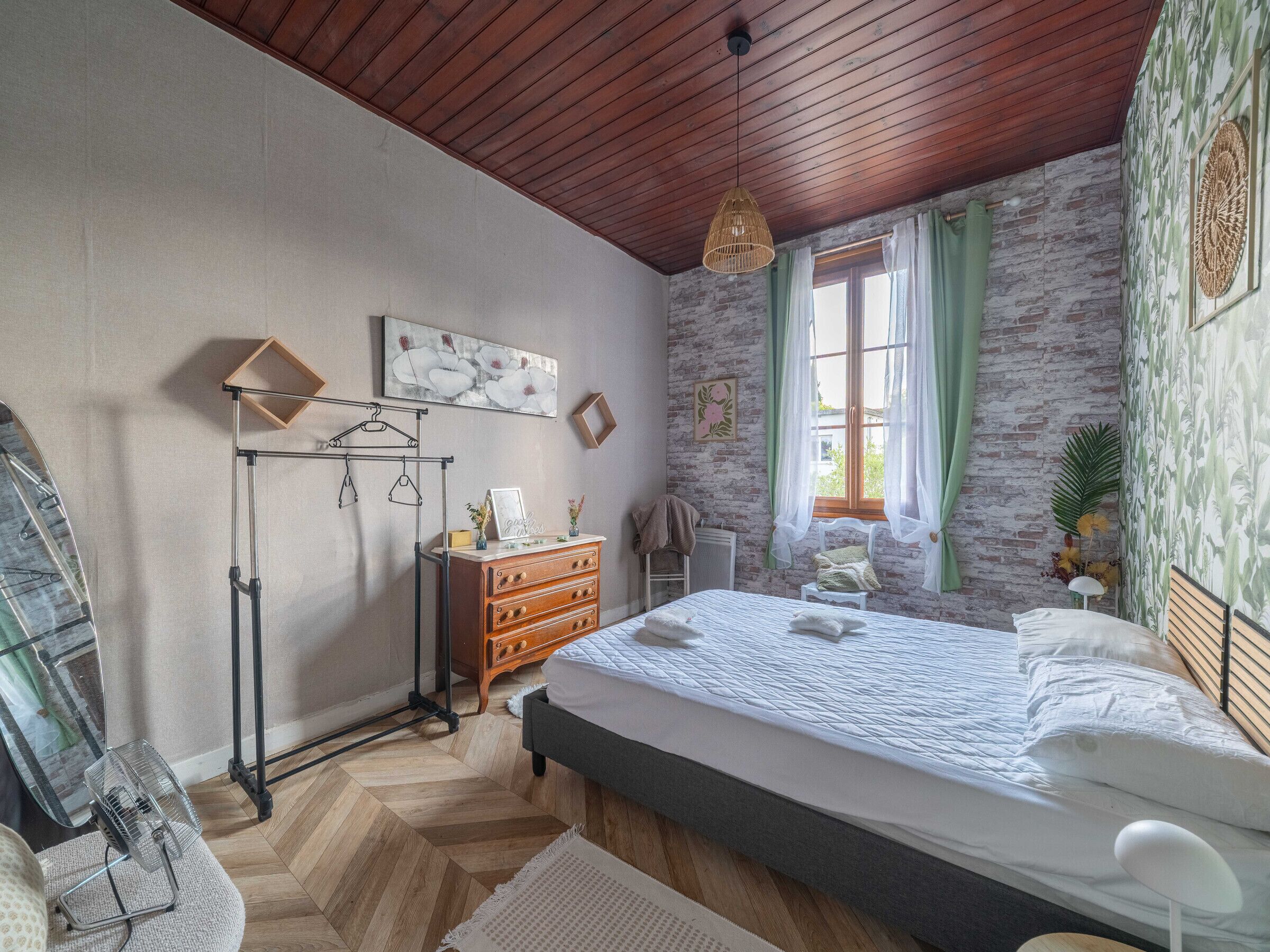Une chambre à coucher avec un lit, une commode et un luminaire suspendu.