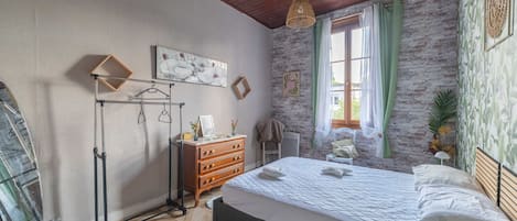 Quarto com cama, cômoda e luminária pendente.