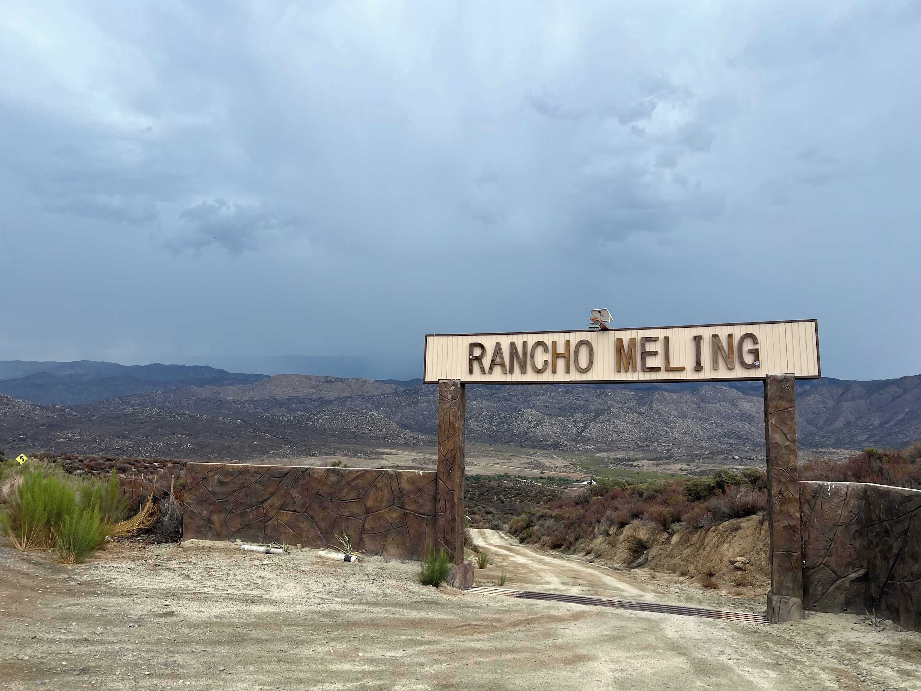 Un panneau indiquant « RANCHO MELING », avec un paysage montagneux en arrière-plan.
