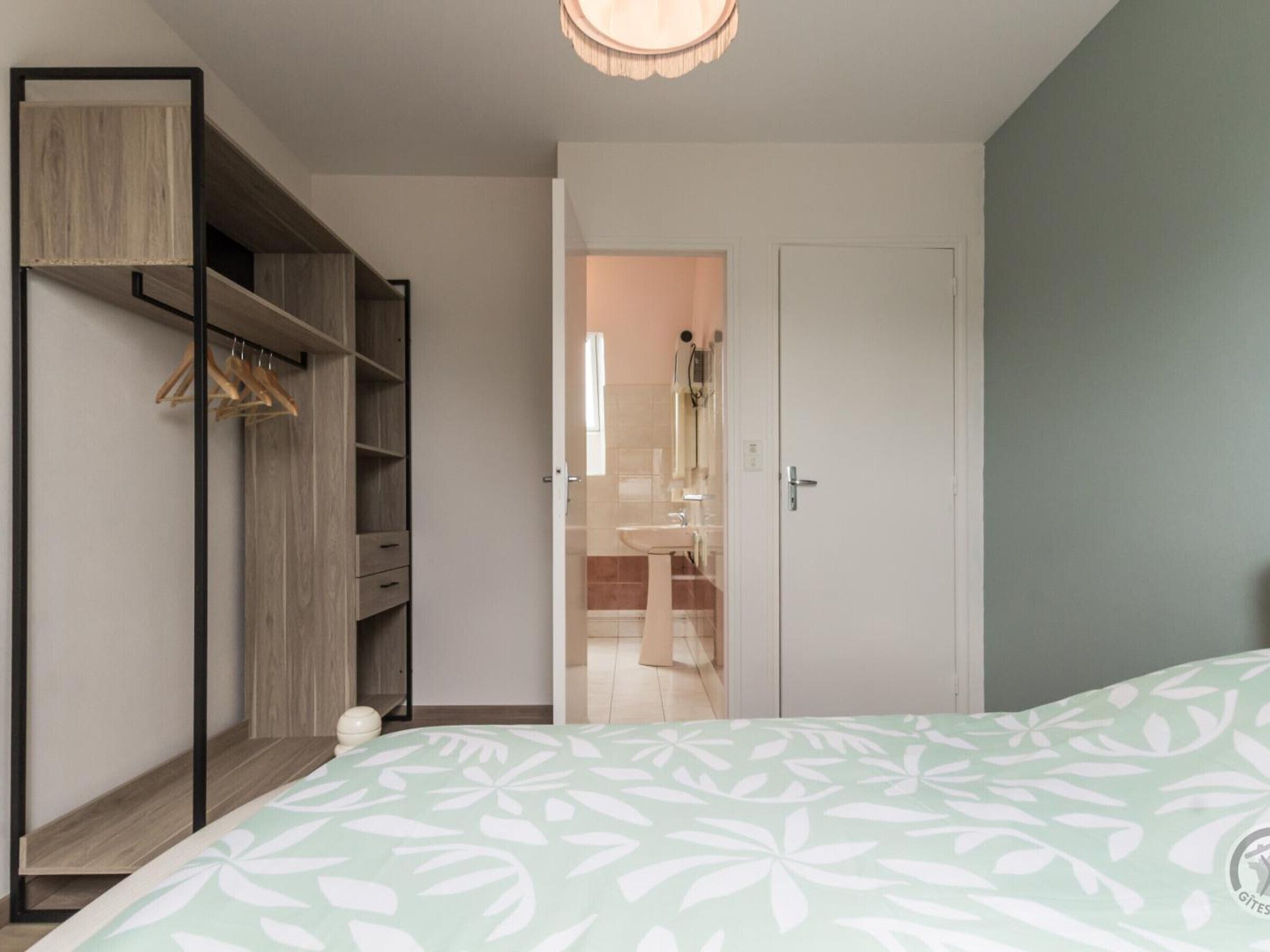 A bedroom with a bed, a wardrobe, and a bathroom visible through an open door.