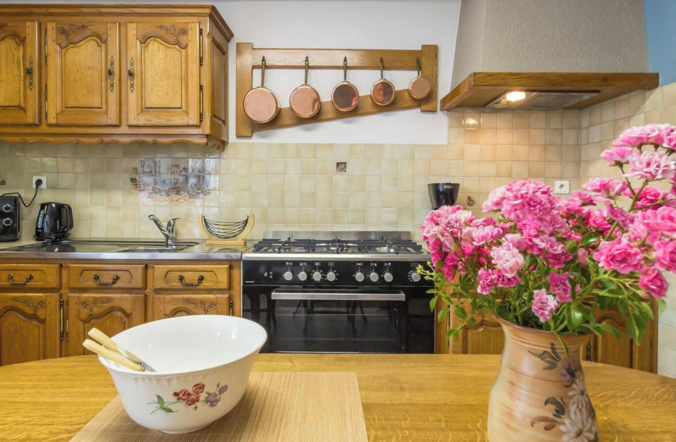 Una cocina con gabinetes de madera, estufa y un colgador para ollas.