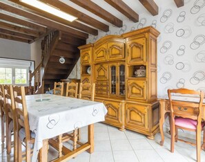 A dining area with a wooden table and chairs, a large wooden cabinet with glass doors, and a patterned wall. - Spacious house with parking - 6 guests (Les Loges-Marchis)