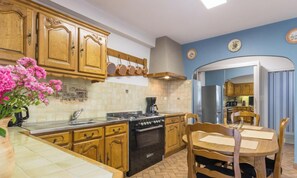 A kitchen with wooden cabinets, a stove, and a dining table with chairs. - Spacious house with parking - 6 guests (Les Loges-Marchis)