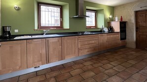 Eine Küche mit einer langen Arbeitsplatte, Holzschränken, einem Gasherd und einem Fenster.