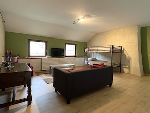 A room with a bunk bed, a television, a dining table, and a sofa.