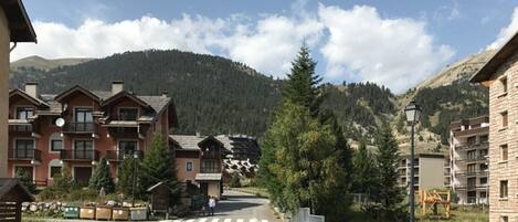 A mountain resort with multi-story buildings, a crosswalk, and a clear view of the surrounding forest and hills.