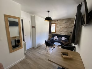 Ein modernes Wohnzimmer mit einer Couch, einem Esstisch und einer Pendelleuchte.
