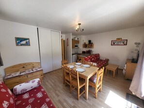 A compact living space with a dining table, wooden furniture, a kitchenette, and a red sofa. - Apartment "La Doire" on the slopes - 3 guests (Montgenèvre)