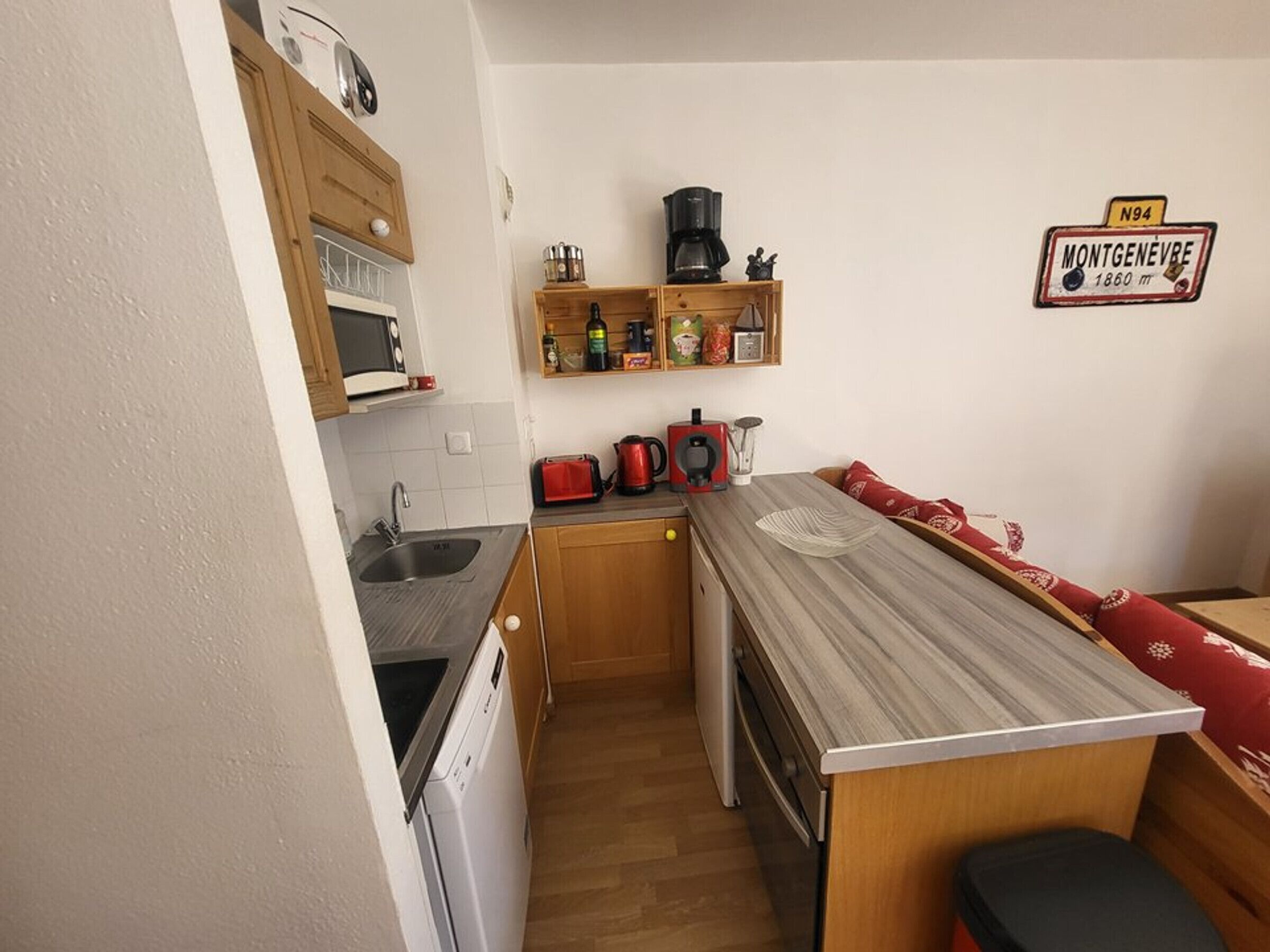 Una kitchenette compacta con microondas, cafetera y un refrigerador pequeño.