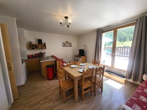 Une cuisine compacte avec des meubles en bois, un évier et un coin repas avec une table dressée pour quatre personnes.