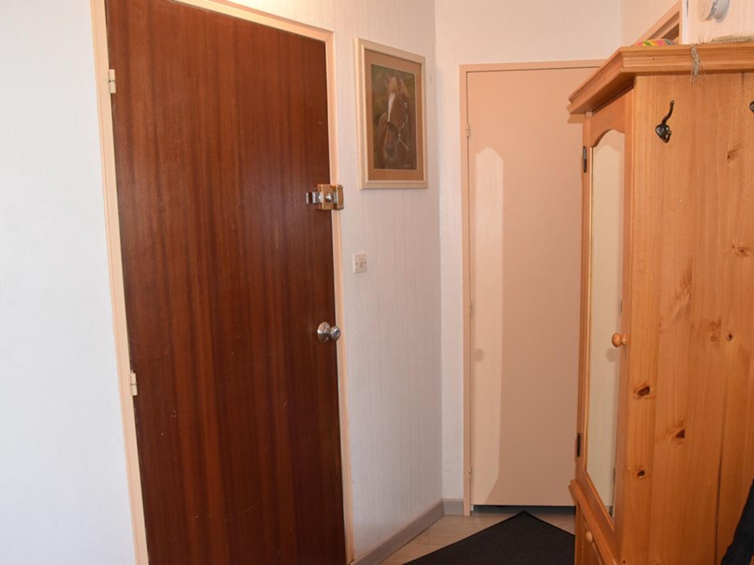Une porte en bois, un mur blanc et un meuble en bois.