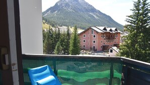 A balcony with a blue chair, a green mesh screen, and a mountain view. - Apartment with village and slopes view - 6 guests (Montgenèvre)