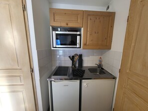 Eine kompakte Küche mit Mikrowelle, Spüle und kleinem Kühlschrank.