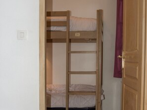 Ein Stockbett mit einer Leiter, eine Tür mit Griff und ein Lichtschalter an der Wand.