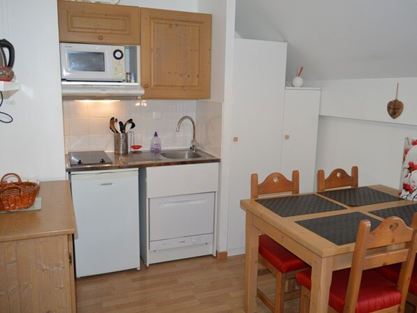 A compact kitchen with a microwave, sink, and dishwasher. There is a dining table with chairs and a basket on the counter. - Studio Montgenèvre view, pets welcome - 4 guests (Montgenèvre)