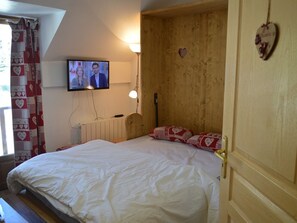 A bedroom with a wooden headboard, a television mounted on the wall, a bedside lamp, and heart-shaped decorations. - Studio Montgenèvre view, pets welcome - 4 guests (Montgenèvre)
