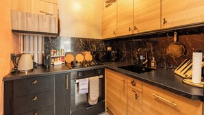 Una cocina moderna con armarios de madera, encimera negra, estufa y lavabo.