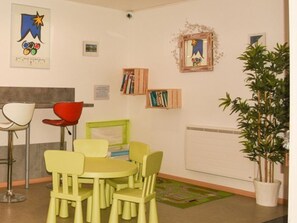 Ein Zimmer mit Tisch und Stühlen, einem Bücherregal und einem gerahmten Bild an der Wand.