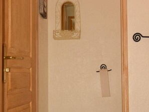Eine Holztür mit Messinggriffen, ein kleines Spiegelbild darüber und ein Wandspender für Handtücher.
