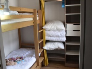 Ein Etagenbett mit kleinem Schreibtisch und Ablagefläche für Kissen.