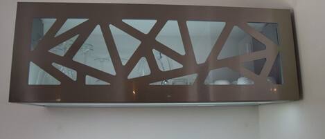 En modern väggmonterad spegel med geometriska utskärningar.