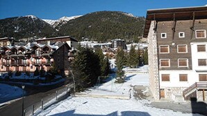 A snow-covered ski resort with traditional chalet-style buildings, a clear sky, and a mountain in the background. - Studio cabin facing slopes - Pets OK (Montgenèvre)