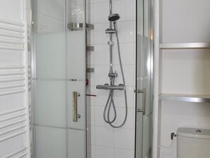 Eine begegnete Duschkabine mit Handbrause und am Wand montiertem Wasserhahn.