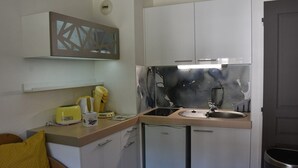 A compact kitchen with white cabinets, a sink, and a countertop. There is a yellow toaster and a coffee maker on the counter. - Studio cabin facing slopes - Pets OK (Montgenèvre)