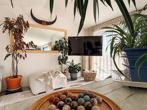 A living room with a wooden coffee table, potted plants, a television, and a large mirror on the wall.