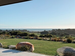 A view from a window overlooking a grassy landscape with a clear sky.