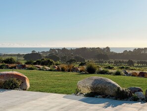 A landscaped garden with large rocks, a paved walkway, and a view of the ocean.