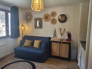 Ein Wohnzimmer mit blauem Sofa, einem Holzkabinett, einer Wanduhr und dekorativer Wandgestaltung.